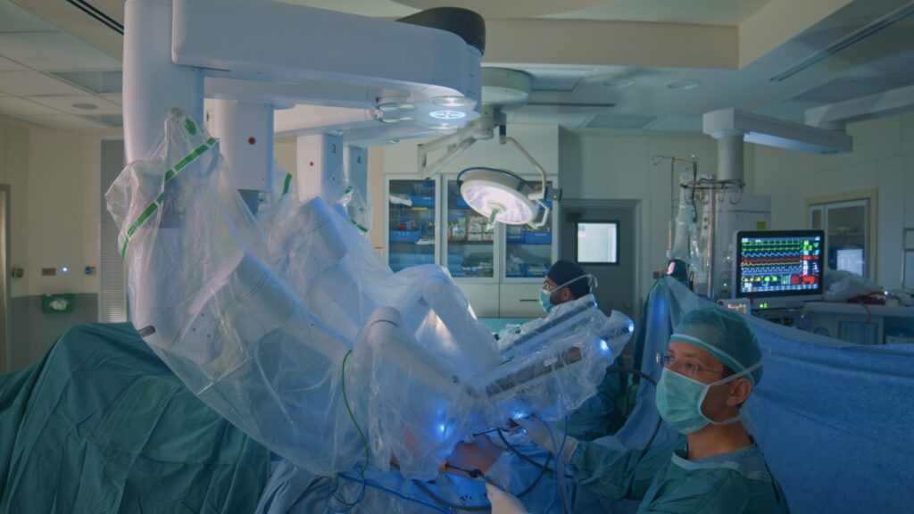 Surgeon looks at the monitor while doing laparoscopic surgery with the help of nurses with a medical robot